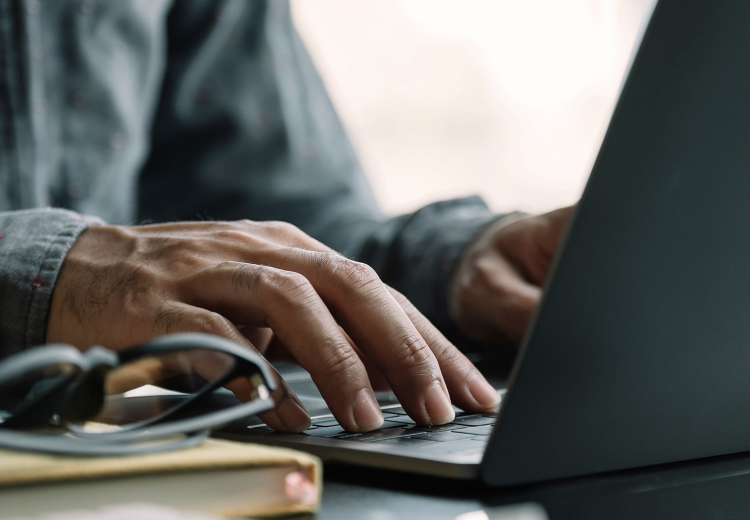 A hand resting on a laptop keyboard.